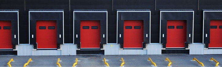 Six closed roller shutters in a dark warehouse.